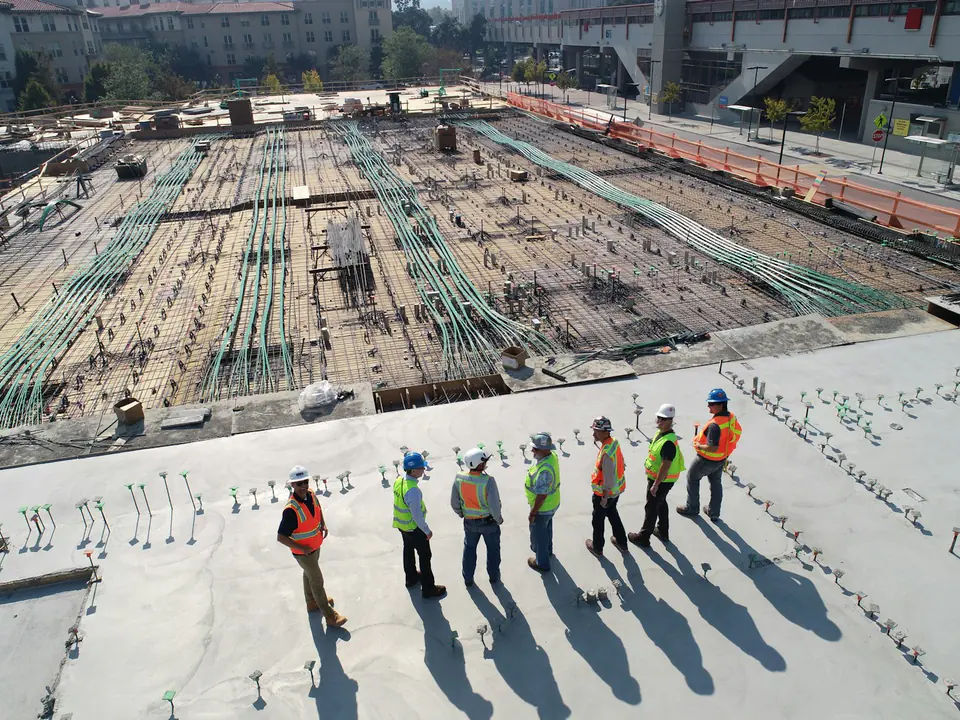 Bauarbeiter stehen nebeneinander auf einer großen Betondecke im Rohbau